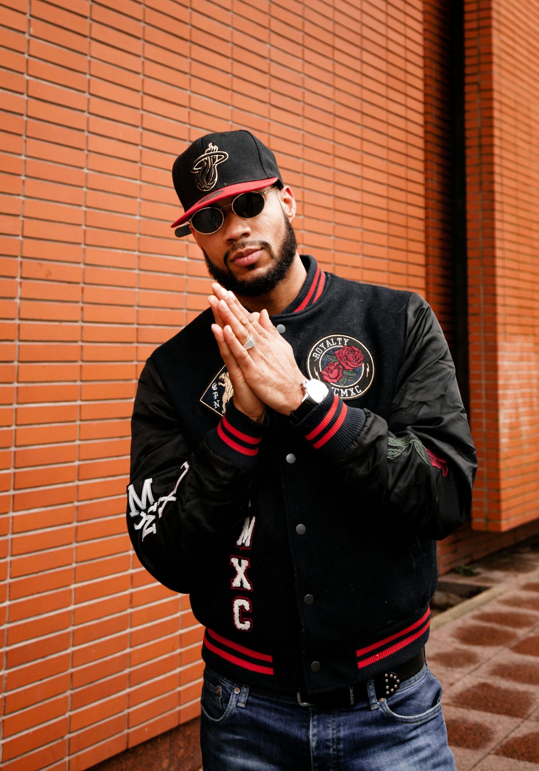 Fashionable bearded man posing in a city with a brick wall background.